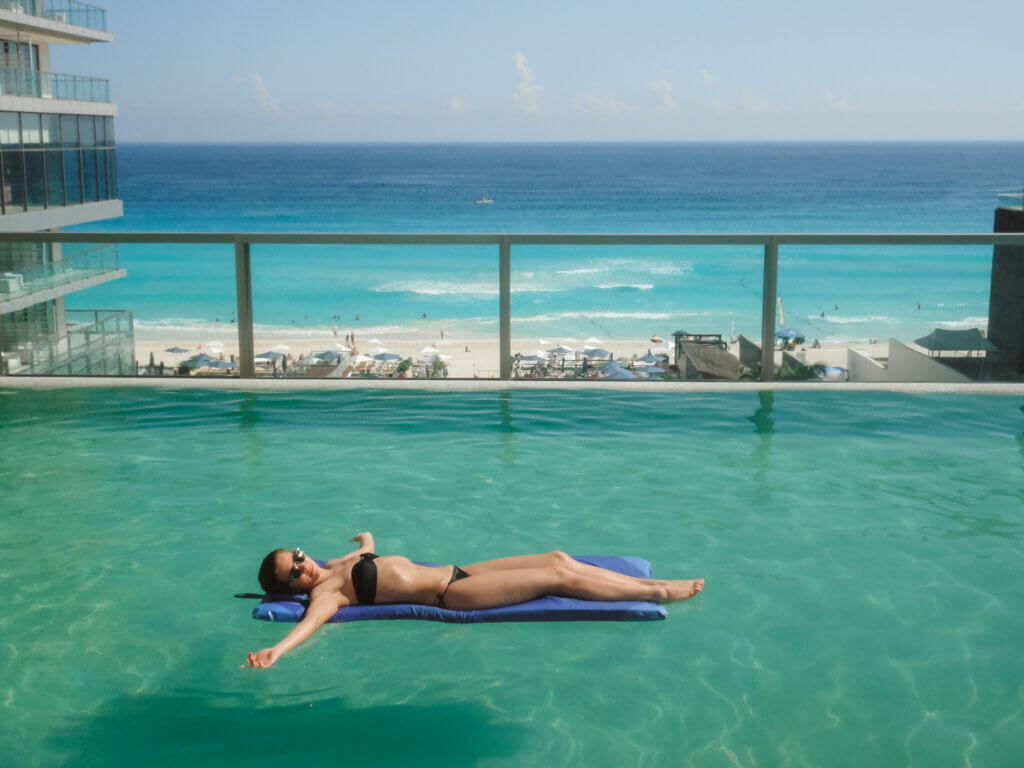 A girl floating in the pool by the beach in Cancun, Mexico